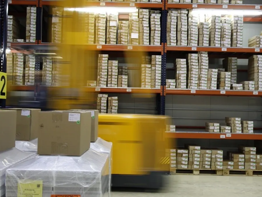 Pallets and cartons being moved into high-level racking in a distribution warehouse